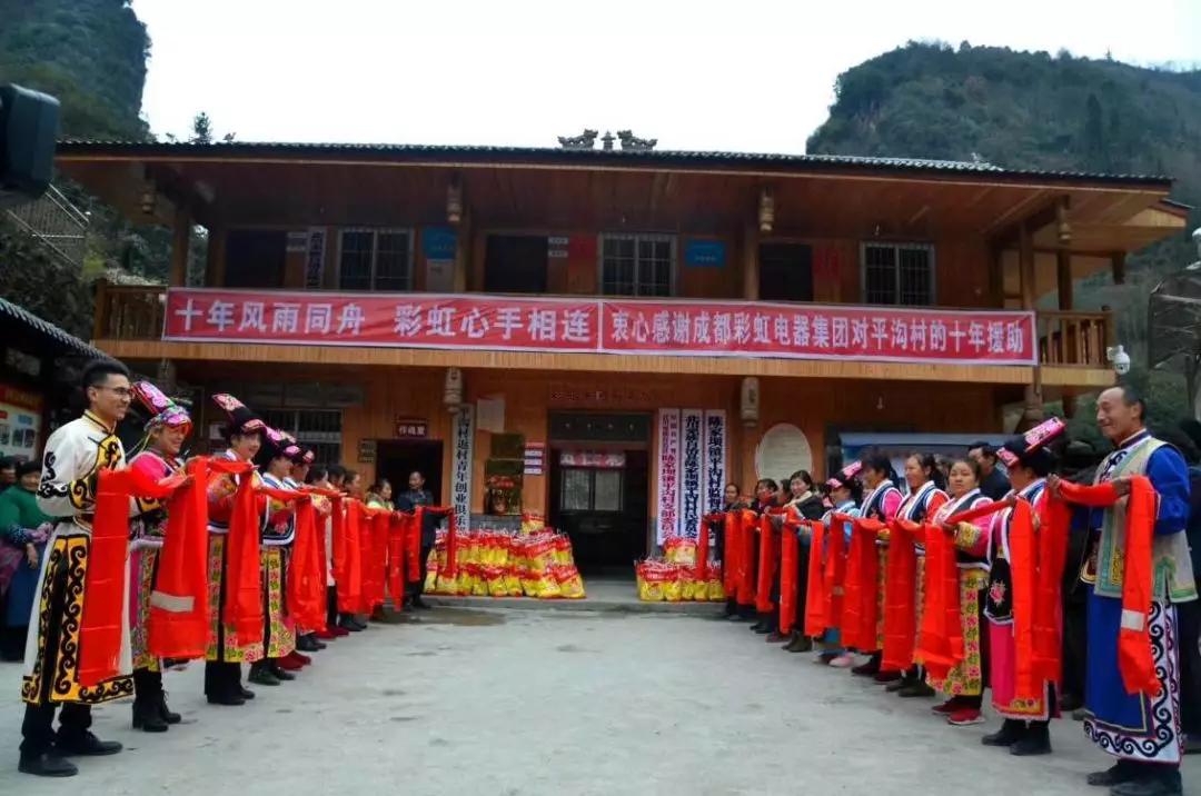 怀感恩之心，平沟村村民手持羌红在milan米兰(中国)体育官方网站公司援建的平沟村便民服务楼前热情等待milan米兰(中国)体育官方网站亲人们的到来